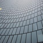 Curved glass side of building, one window is lit up.