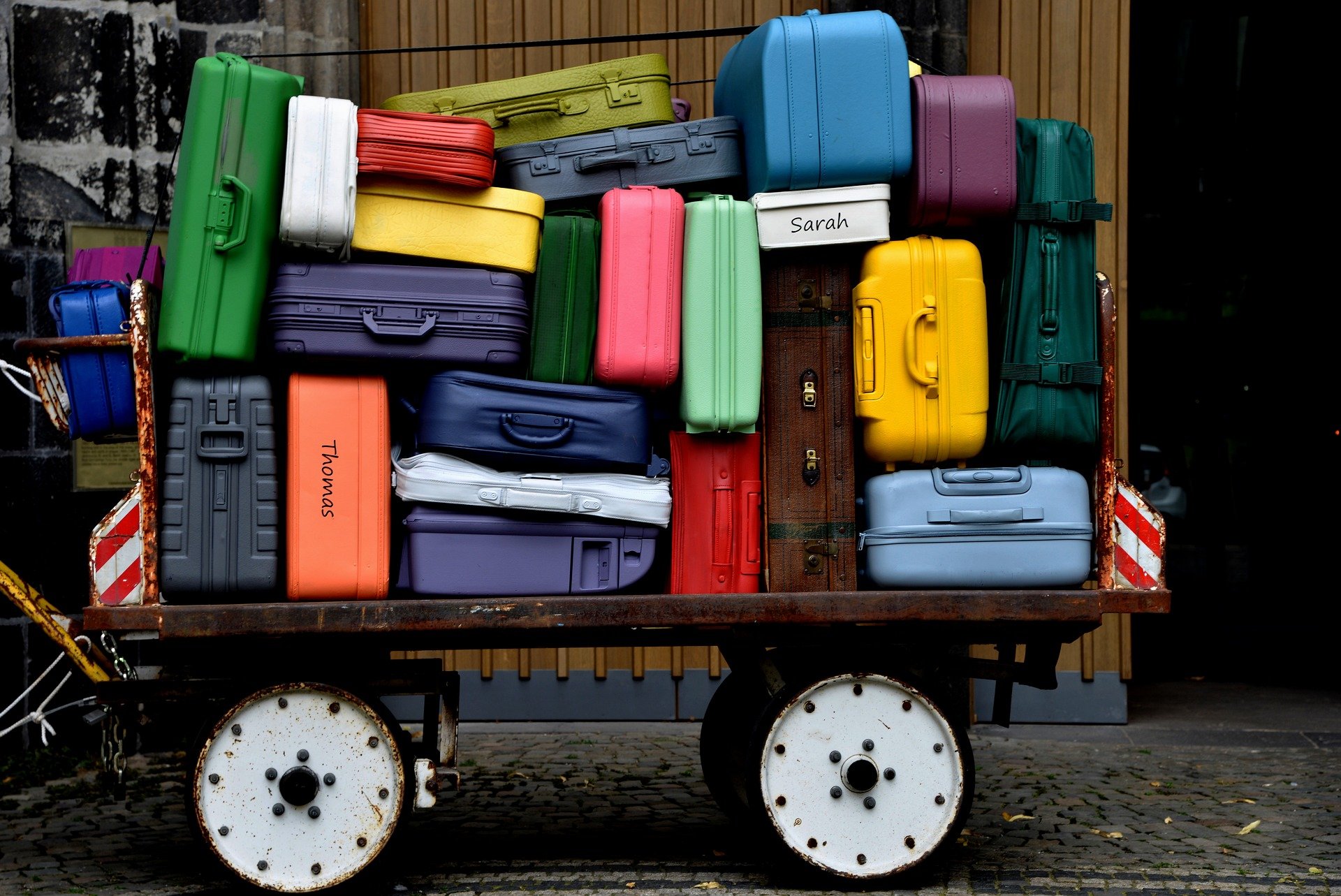 Luggage cart piled up with colorful luggage.