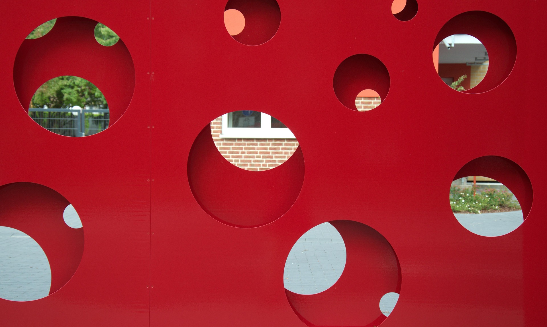 playground wall with holes, showing clues to a home behind it.