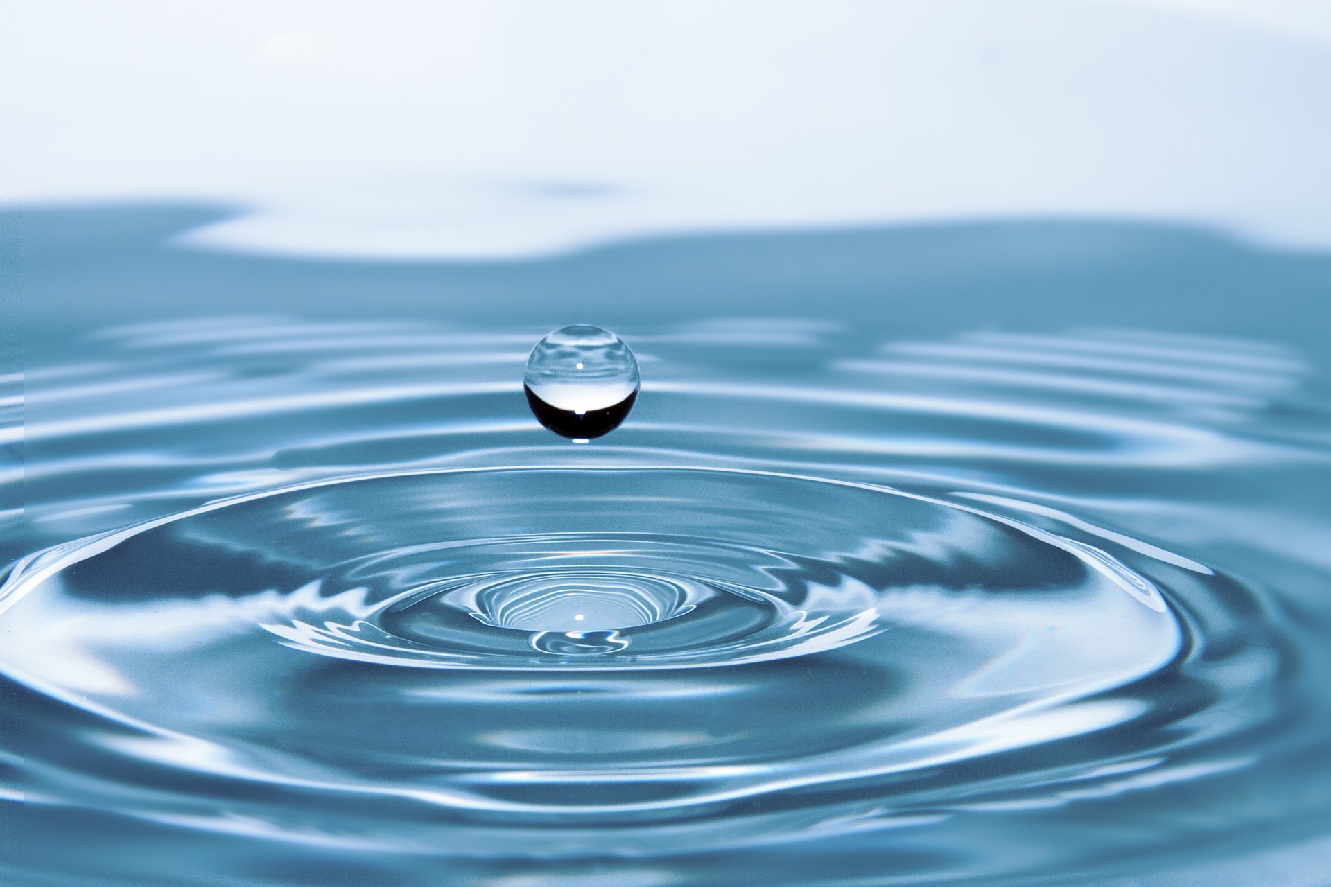 Drop of water falling into pool of water, rippling.
