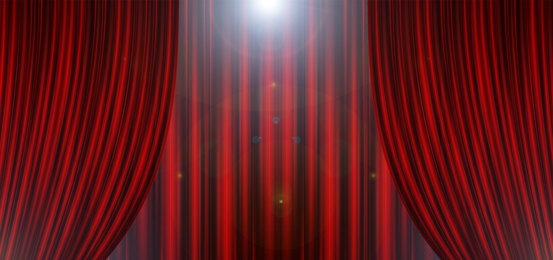 Curtains opening on a lighted theater stage.