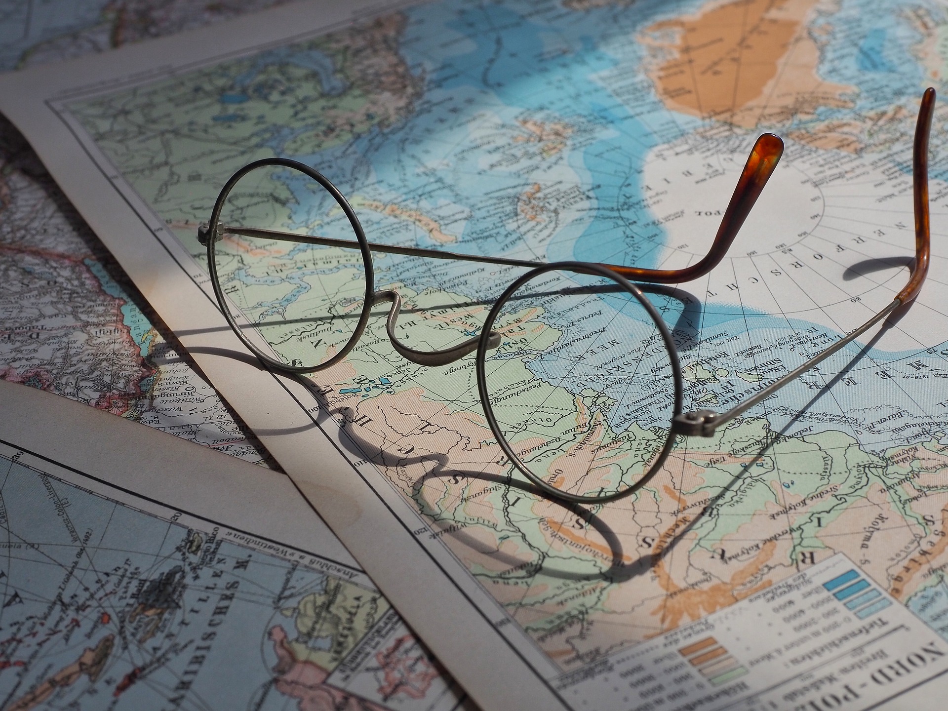 Glasses resting on some world maps.