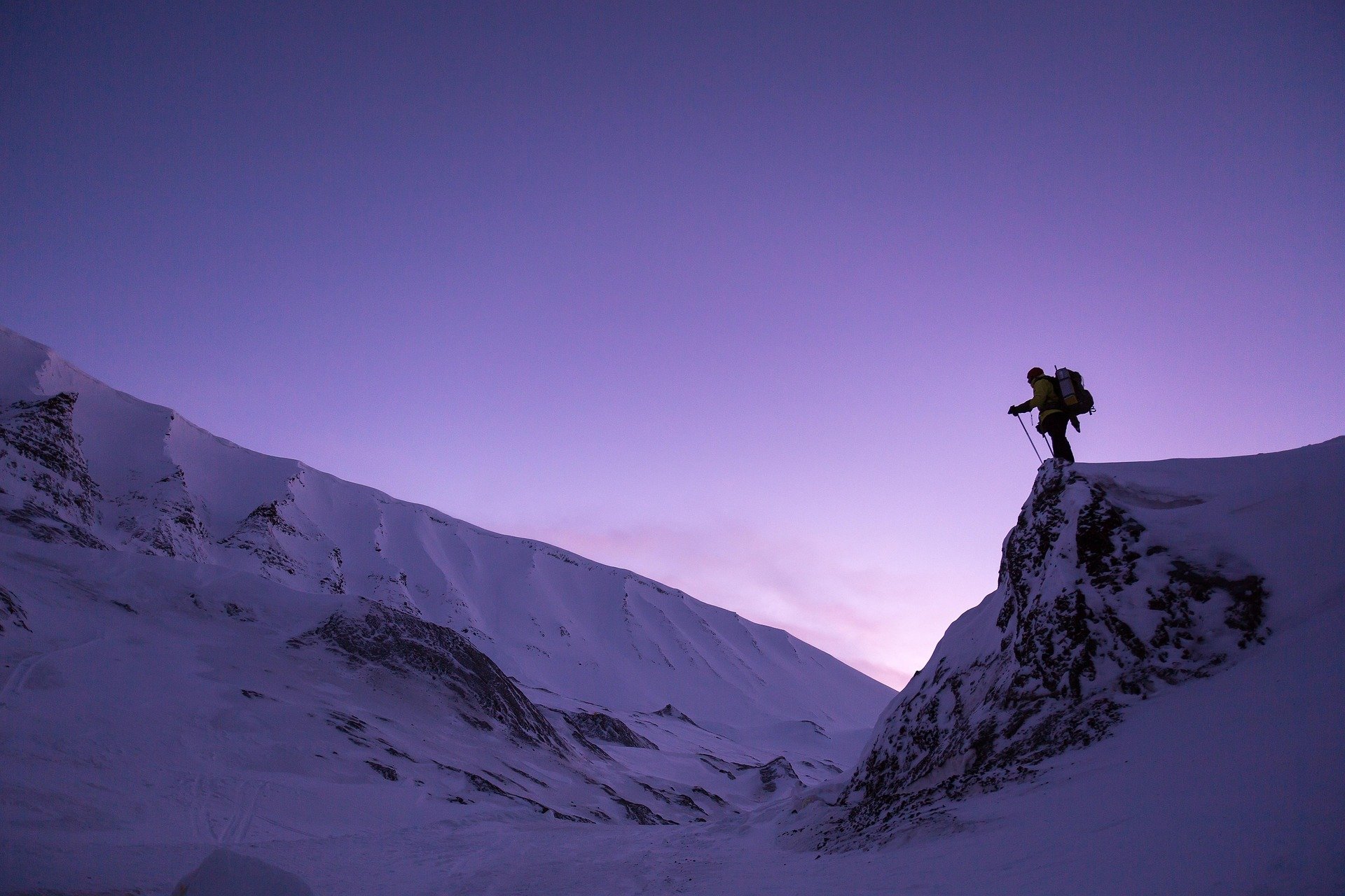 Mountain climber reaching the summit of snowy peaks.