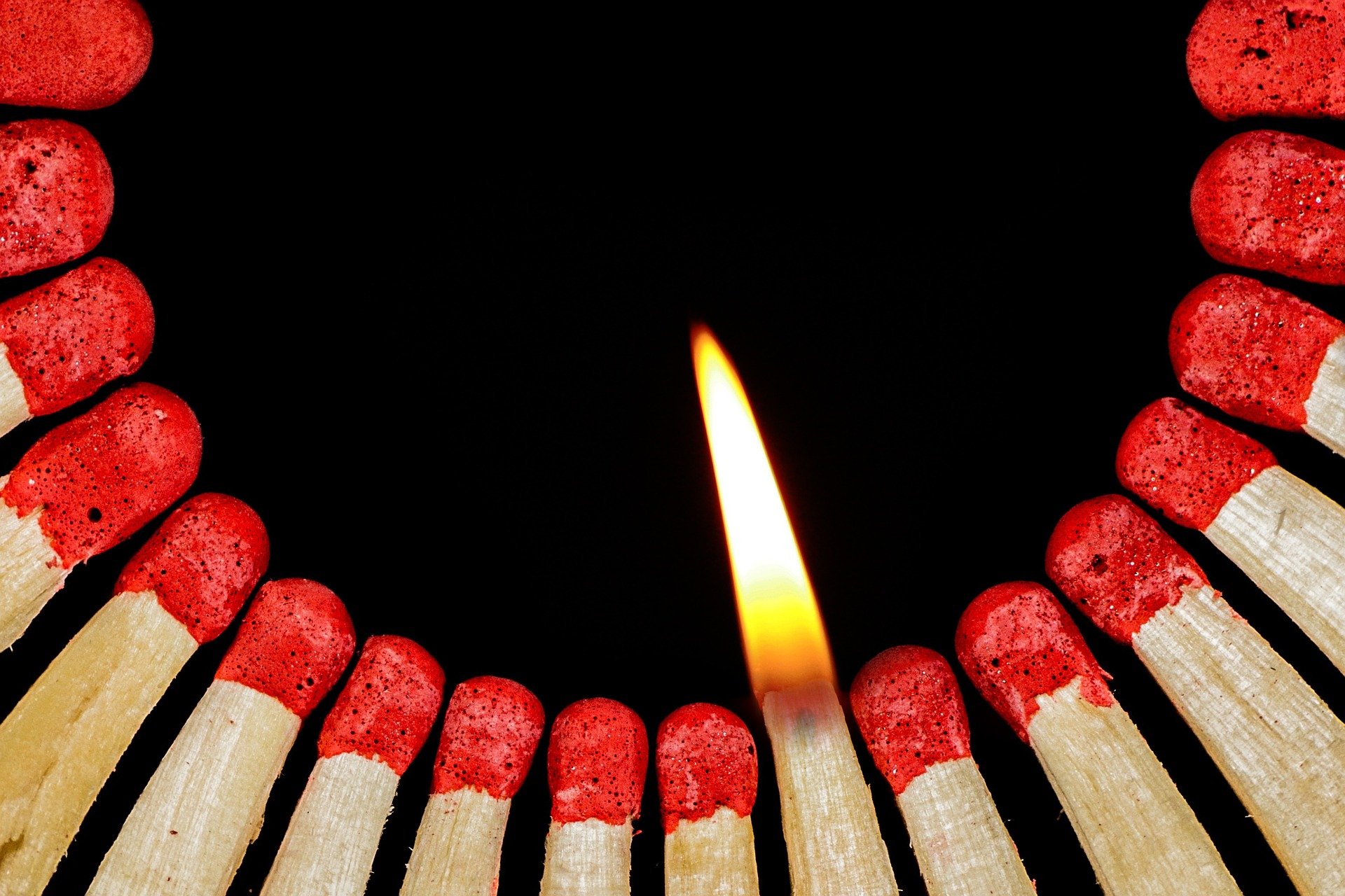 A grouping of matches with one lit up.