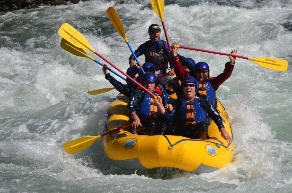 A team of white water rafters cheering, holding up their oars.