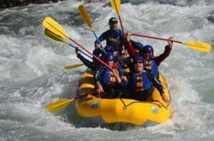 A team of white water rafters cheering, holding up their oars.