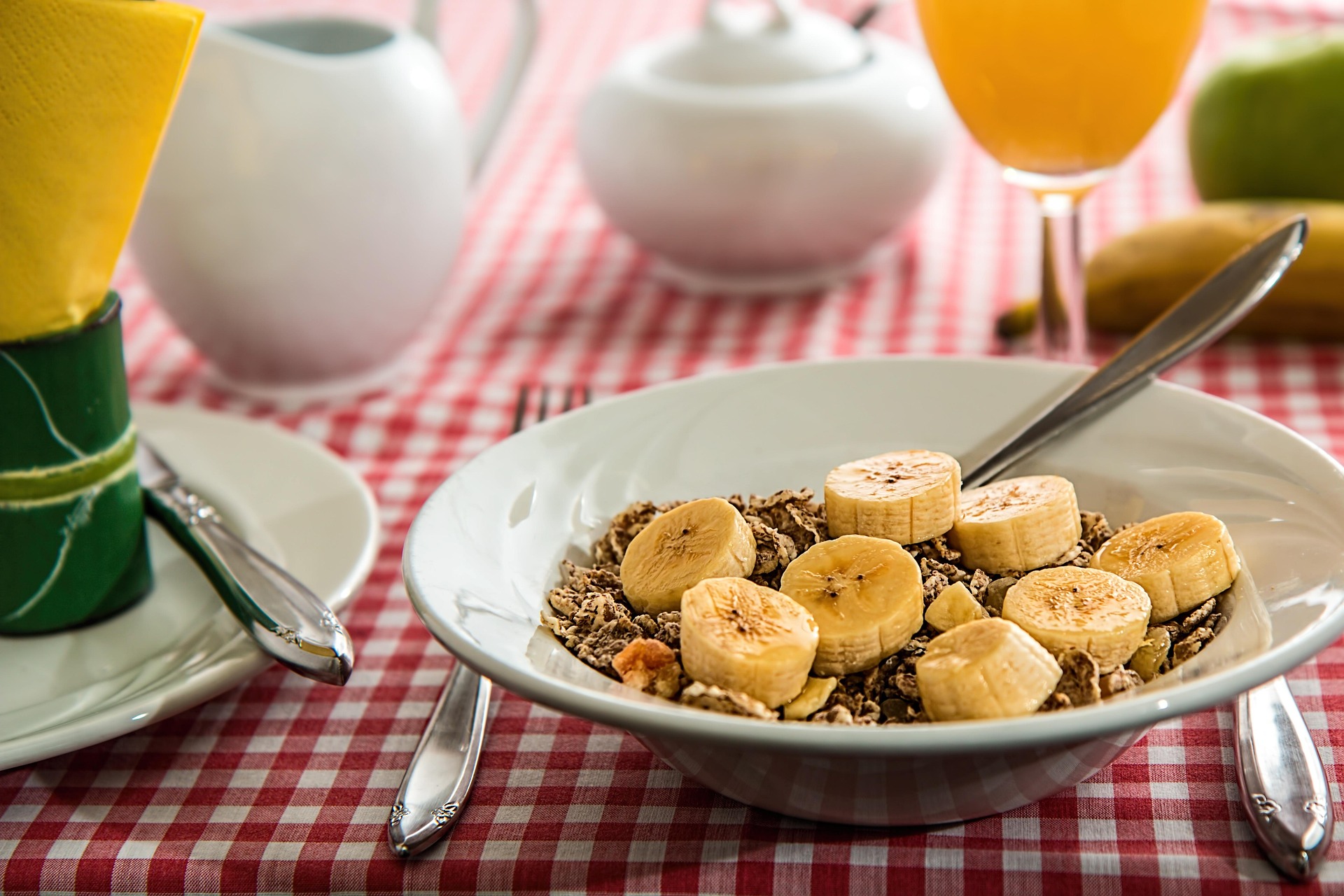 Breakfast cereal with bananas on table setting.