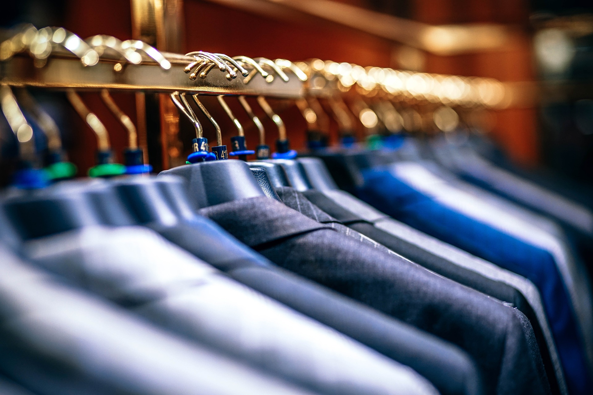 A retail store display of suit jackets on hangers.