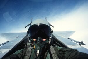 Human fighter pilot in the cockpit of a fighter jet.