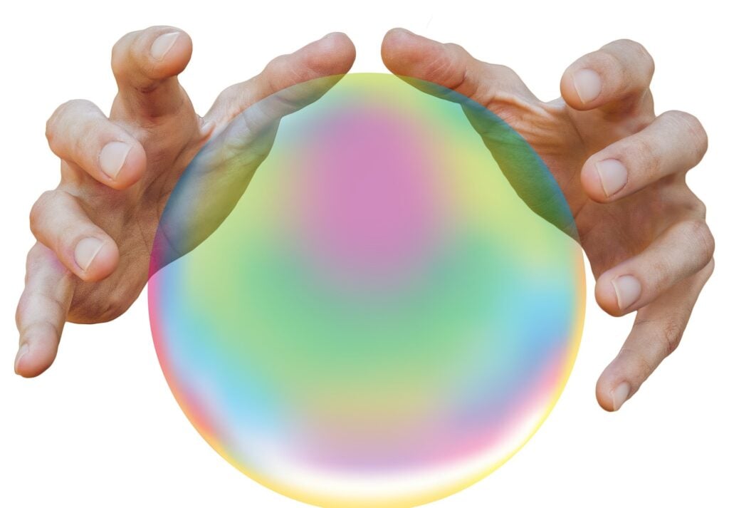 Two hands hovering over crystal ball.