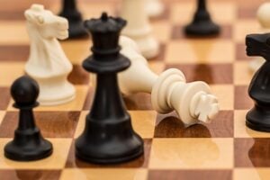 Checkmate on a chess board with queen looming over the fallen king.
