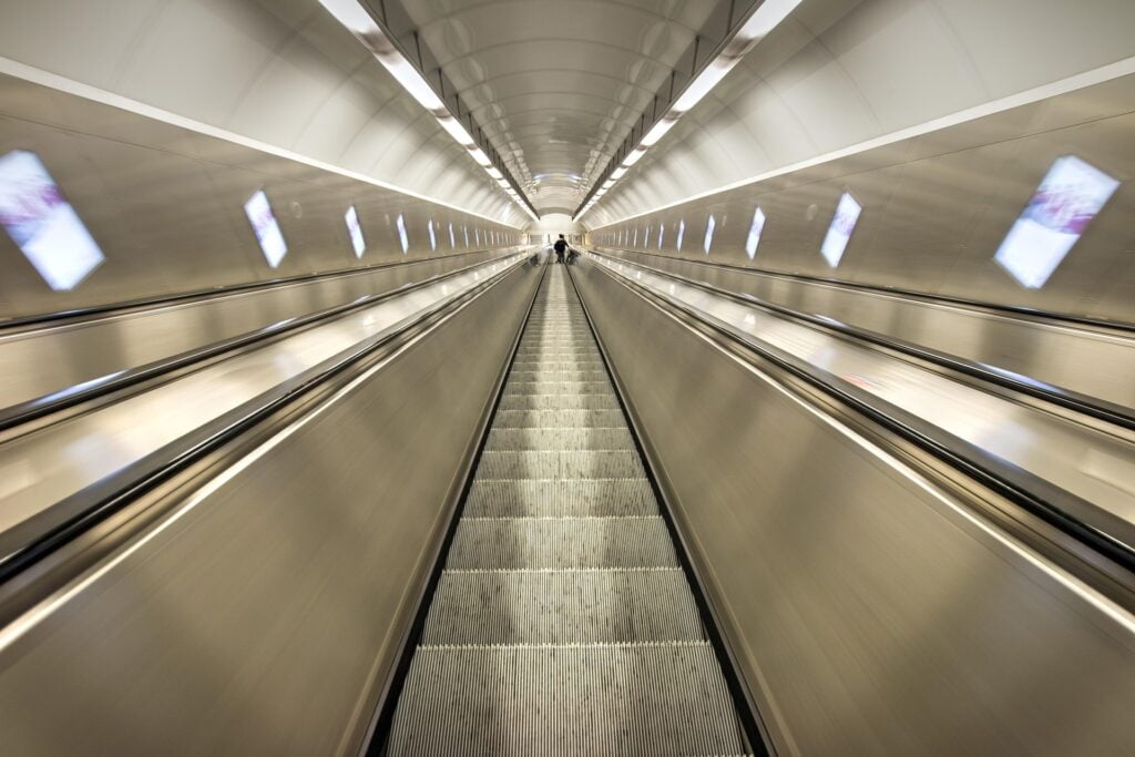 The perspective of going up or down a long escalator like in a subway.
