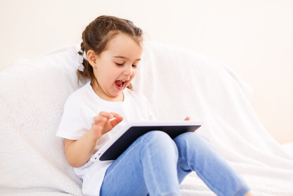Young girl enjoying and watching a tablet device.