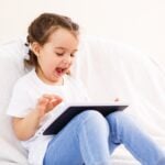 Young girl enjoying and watching a tablet device.