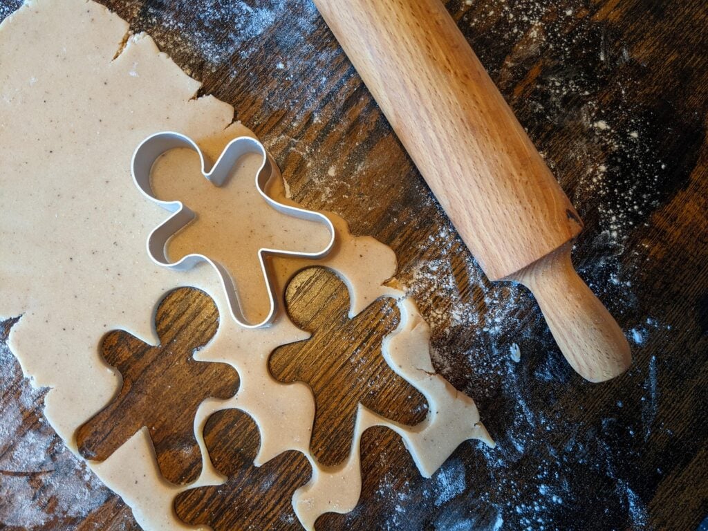 Cookie cutters of gingerbread men, with dough shapes, rolling pin and flour.