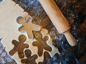 Cookie cutters of gingerbread men, with dough shapes, rolling pin and flour.