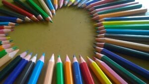 A range of sharp colored pencils outlining a heart shape.