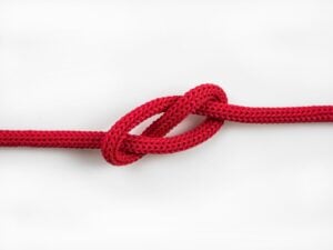 A red woven rope/cord, with a knot in the middle getting loosened up or tightening).