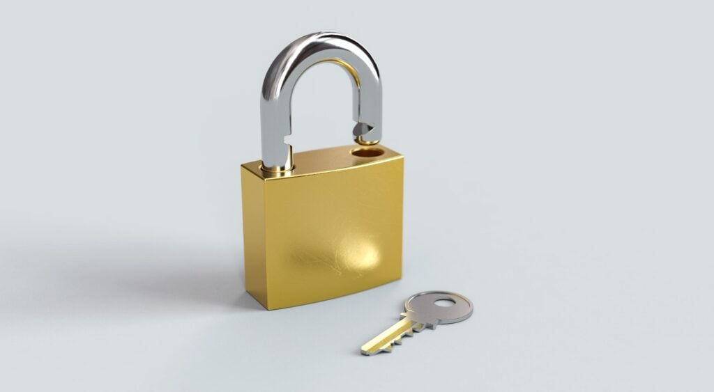 Open golden padlock with key lying next to it.