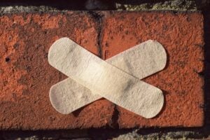 Red brick with crack with two band aids across it.
