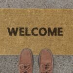 A welcome mat with shoes at the edge, like someone just about to walk in. Says 'Welcome.'