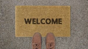 A welcome mat with shoes at the edge, like someone just about to walk in. Says 'Welcome.'