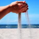 Hands holding and sifting sand at the beach.