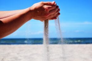 Hands holding and sifting sand at the beach.