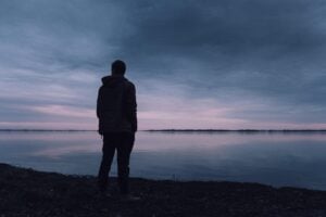 Silhouette of man by a lake as it gets dark, symbolizing the consumer for next year amid uncertainty.