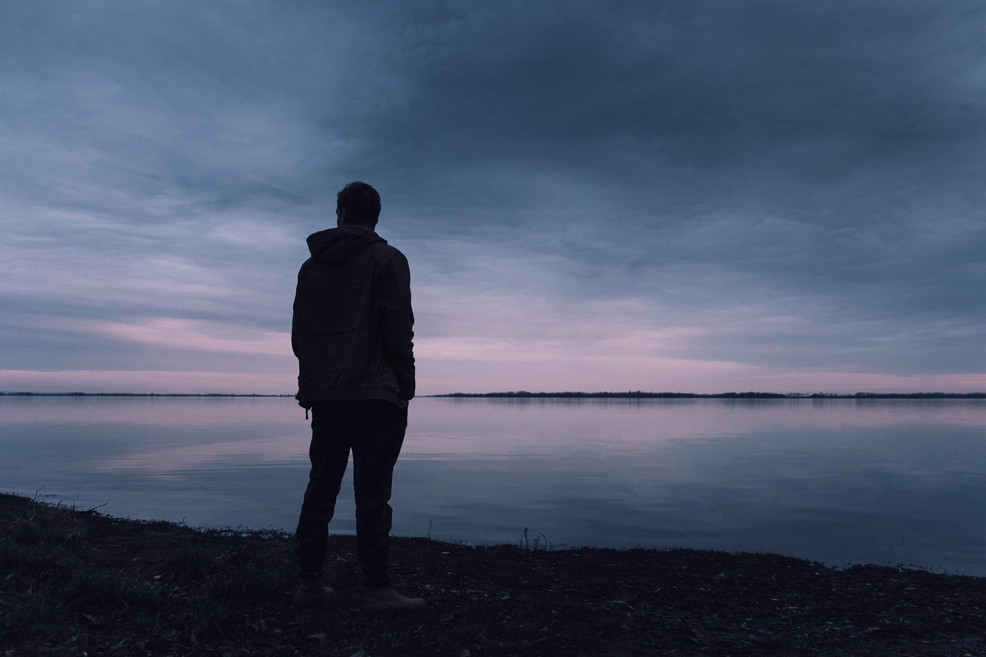 Silhouette of man by a lake as it gets dark, symbolizing the consumer for next year amid uncertainty.