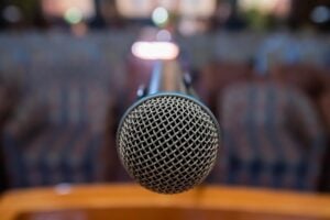 A podium with central microphone looking out into the blurry audience seating.