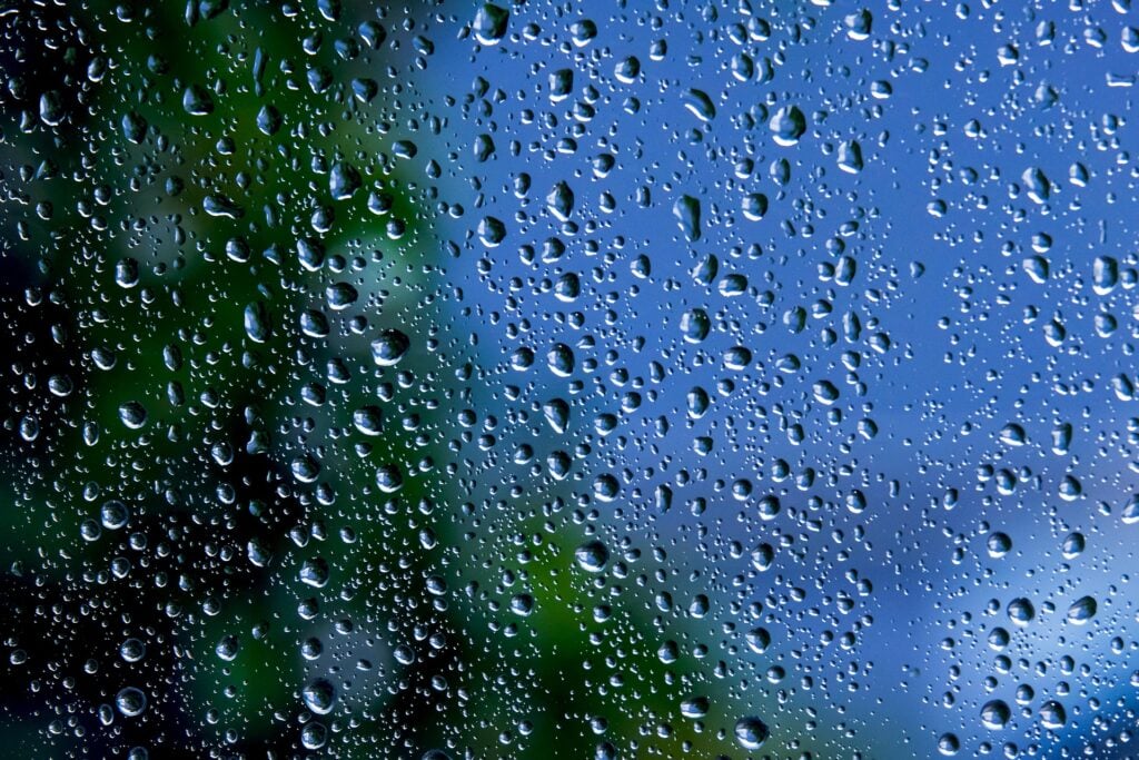 Raindrops on glass, running down the pane and obscuring what's behind.