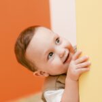 Cute little happy boy peeking around a door or wall.