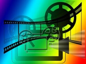 A stylized and colorful film projector graphic showing projector, film and reels.