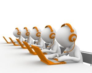 A row of mannequin call center agents with headsets and laptops.