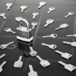 A black and white image showing a padlock surrounded by a grouping of keys.