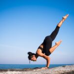 Athletic woman on some rocks balancing in a strong yoga pose.