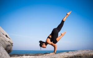 Athletic woman on some rocks balancing in a strong yoga pose.