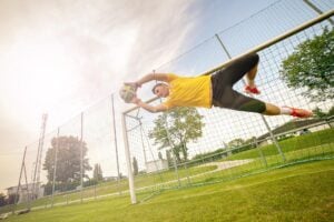 Soccer goalkeeper diving across the goal to make the save.