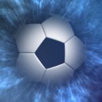 A soccer ball emerging from the fog and in the spotlight.