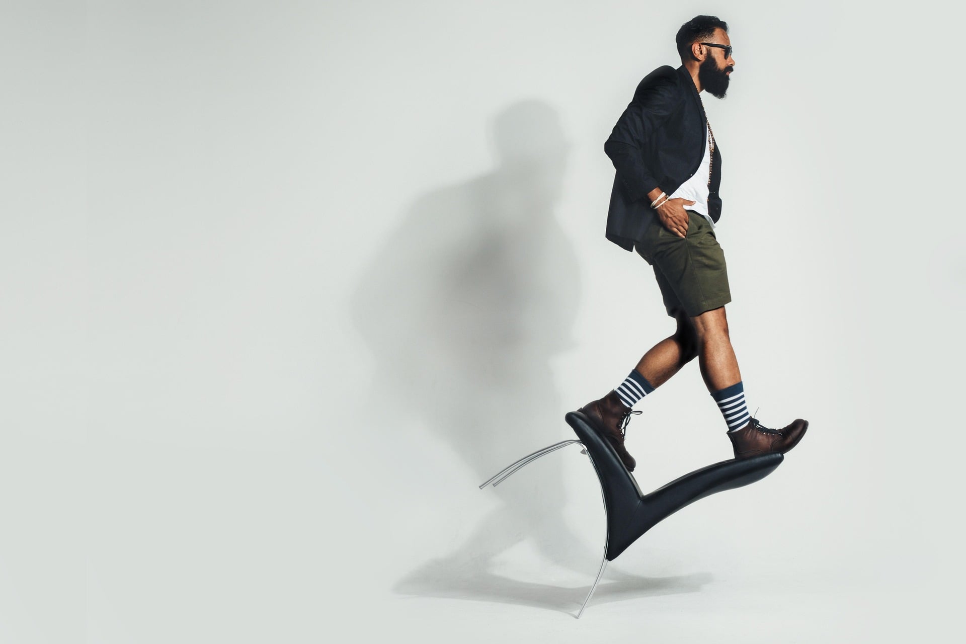 A man balancing and standing on a leaning chair at an impossible angle.