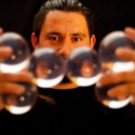 A juggler holding six crystal balls balanced together in his hands.