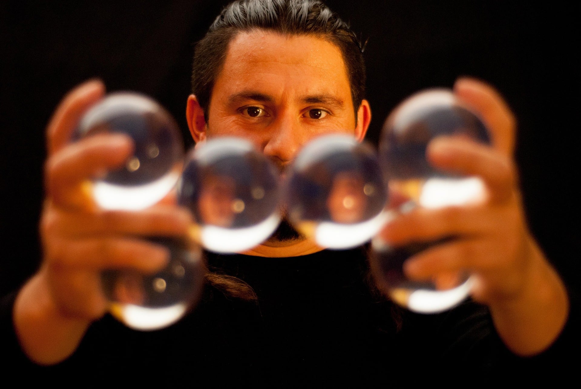 A juggler holding six crystal balls balanced together in his hands.