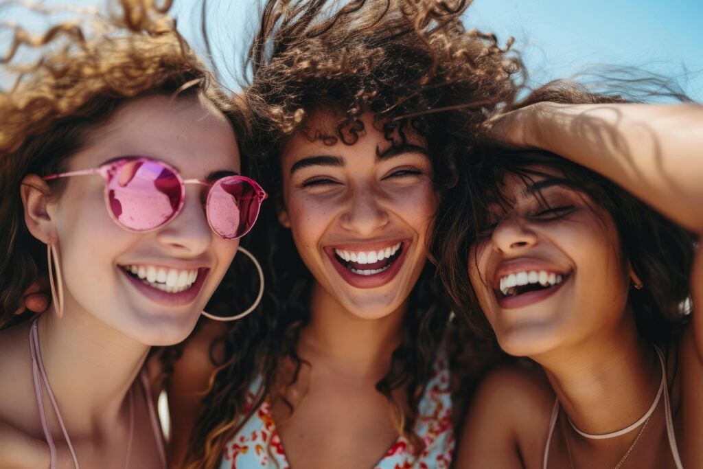 Three happy young girls hugging, smiling and laughing together.