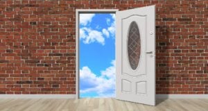 Brick wall with open door in the center, leading to blue sky with clouds.