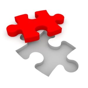 Red puzzle piece ready to placed into a white floor background.