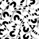 A pile of a lot of question marks on note paper in roughly a circle.