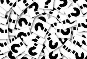 A pile of a lot of question marks on note paper in roughly a circle.