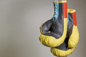 Two boxing gloves hanging down, ready for making an impact.