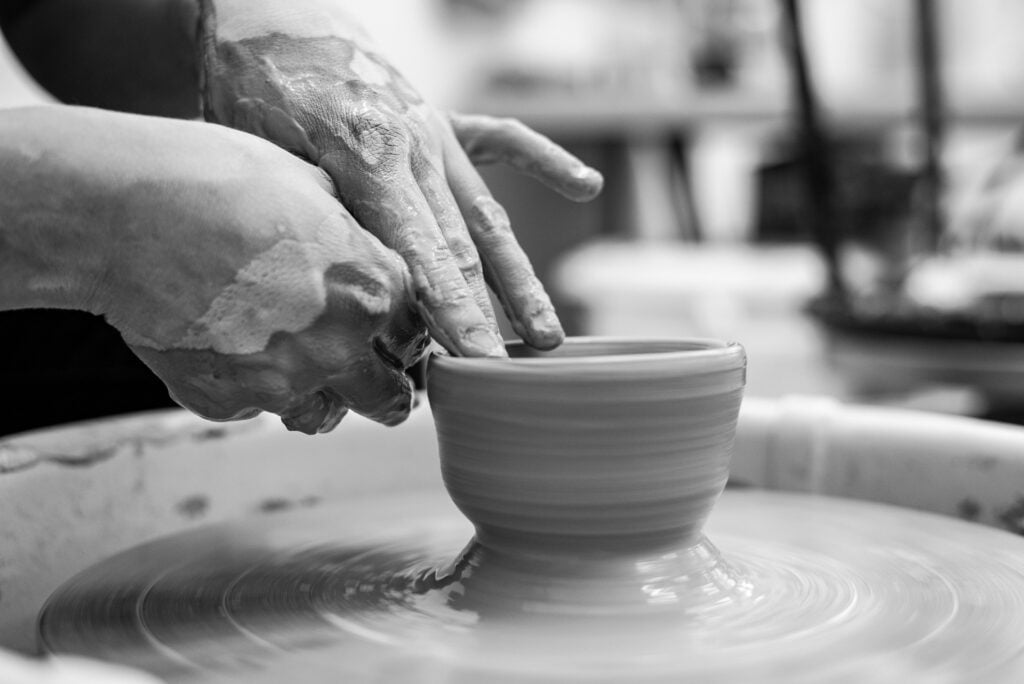Hands shaping a clay pot on the potter’s wheel.